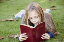 Little girl reading the Bible outdoors