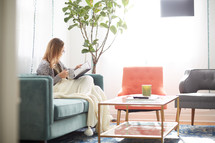 a woman reading a book on a couch 