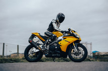 Aprilia RSV4 sports motorbike, superbike motorcycle, yellow racing colours with a female rider in full racing leathers and helmet