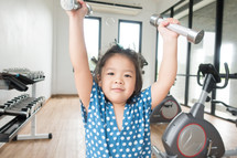 a little girl lifting weights in a gym