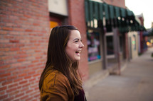 a smiling young woman standing on a sidewalk 