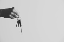 Hand dangling keys from two fingers.