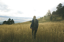 a woman backpacking through a field 
