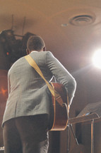 a man singing and playing a guitar at a worship service 