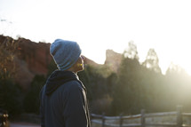 a man standing outdoors in a sweatshirt and beanie 