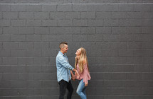a couple standing in front of a gray brick wall 