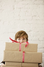 a young boy holding a stack of gifts.
