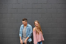 a couple standing in front of a gray wall 