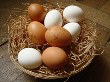 Natural eggs in a basket on a wood floor.