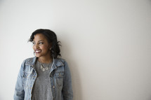 portrait of an African American leaning against a wall in a jean jacket 
