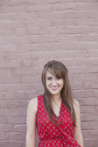 smiling young woman standing in front of a wall 