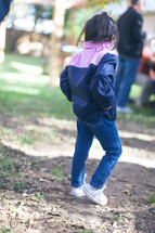 a little girl standing outdoors in a jacket 