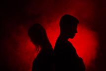 couple standing back to back in red glowing light 