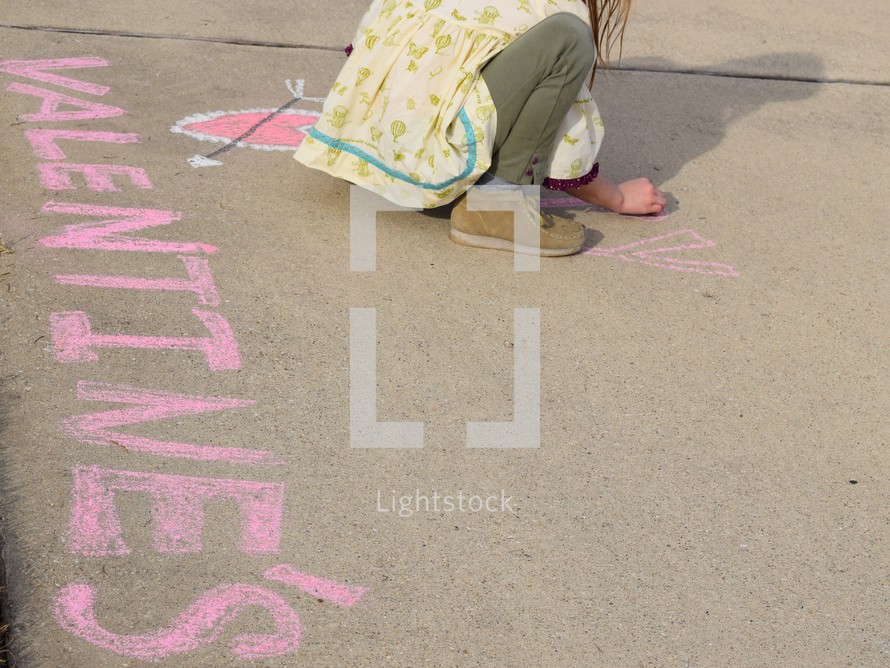 a little girl drawing in sidewalk chalk for Valentine's day 