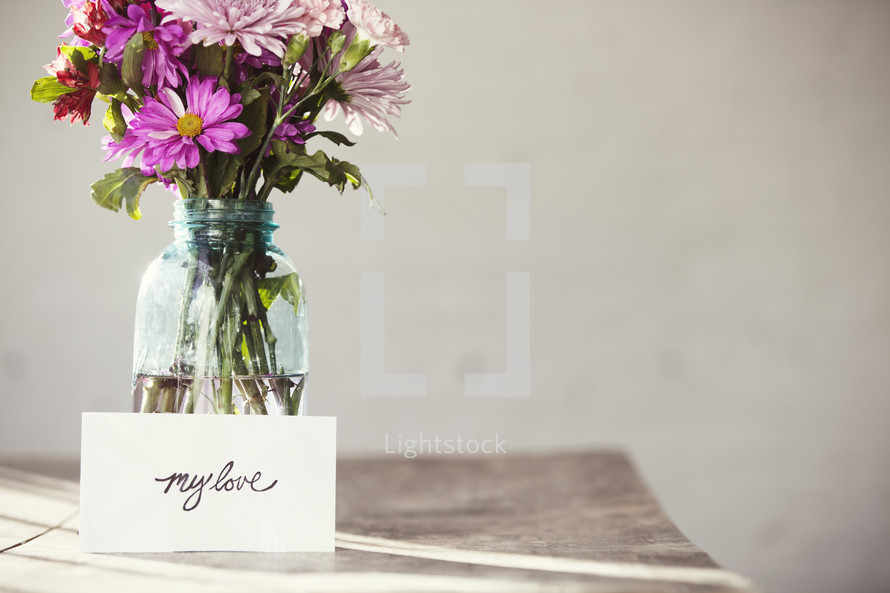 A bouquet of flowers in a vase and a card that reads "my love"