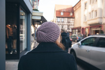 woman walking down a sidewalk in front of store fronts 