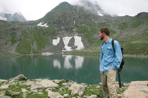 man backpacking next to a mountain lake 
