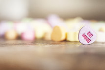 Candy hearts scattered on a wood table.