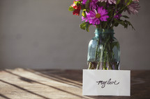 A bouquet of flowers in a vase and a card that reads "my love"
