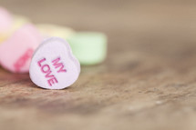 Candy hearts scattered on a wood table.