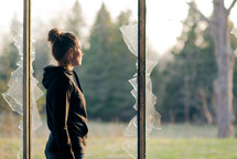 a teen girl standing in a broken window 