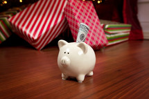 cash in a piggy bank in front of a Christmas tree 