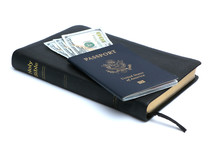 Money in a passport on top of a Bible.