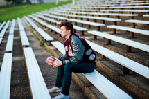 a young man sitting on bleachers holding a football 