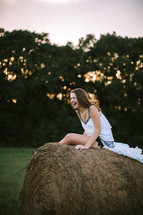 teen girl laughing sitting on a hay bale 