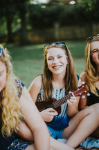 smiling teen girl with braces holding a ukulele 