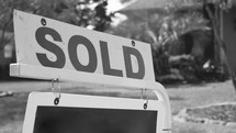 real estate sold sign in front of a house 