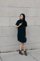 portrait of an Asian young woman standing in front of a concrete wall 