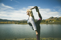a woman stretching and doing yoga by a lake 
