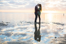 a couple hugging on a beach at sunset 