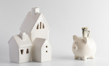 piggy bank and small white houses against a white background 