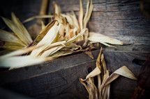 Harvested corn tassels and flint corn cover wooden planks.