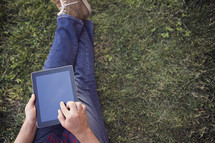 a man sitting in the grass with an iPad 