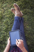 man sitting in the grass with an iPad 