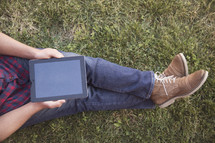 a man sitting in the grass with an iPad 