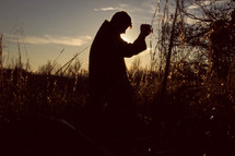 a man kneeling in a field praying 