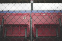 Stadium seats behind a chain link fence.