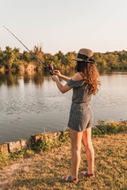young woman fishing on a lake shore 