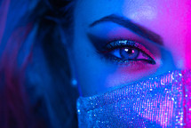 Close up of face in glitter protective mask and make-up under a neon light. 