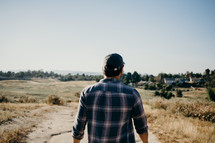a man in a plaid shirt walking outdoors 