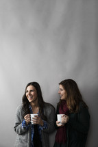 women holding a mug of coffee talking