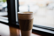 a paper coffee cup in a window sill 