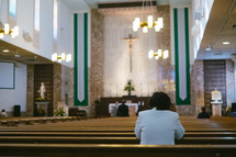 a woman praying in church pews 