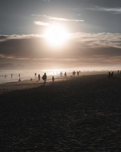 people walking on a beach at sunset 