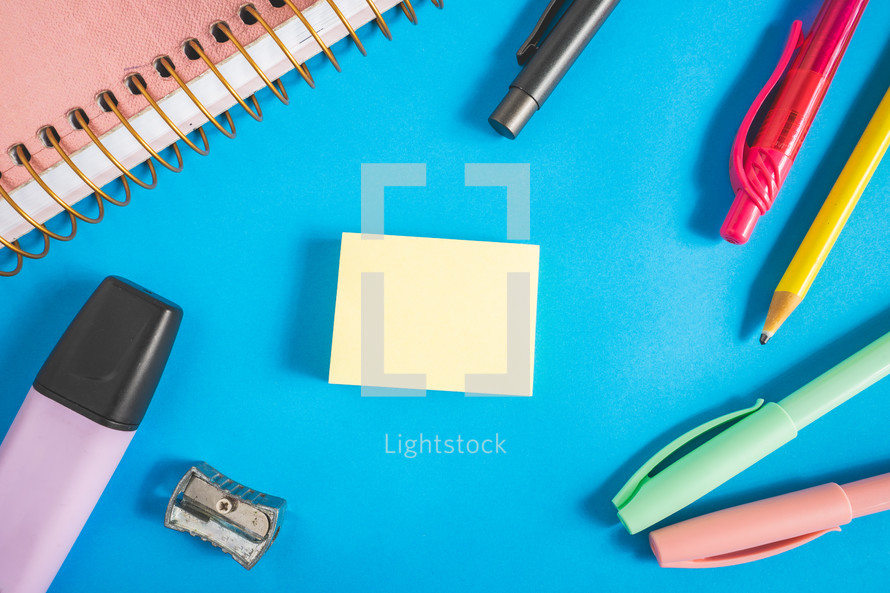 Different kind of school/office supplies for studying, on a blue background. Back to school.