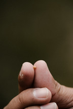 fingers holding a tiny mustard seed 